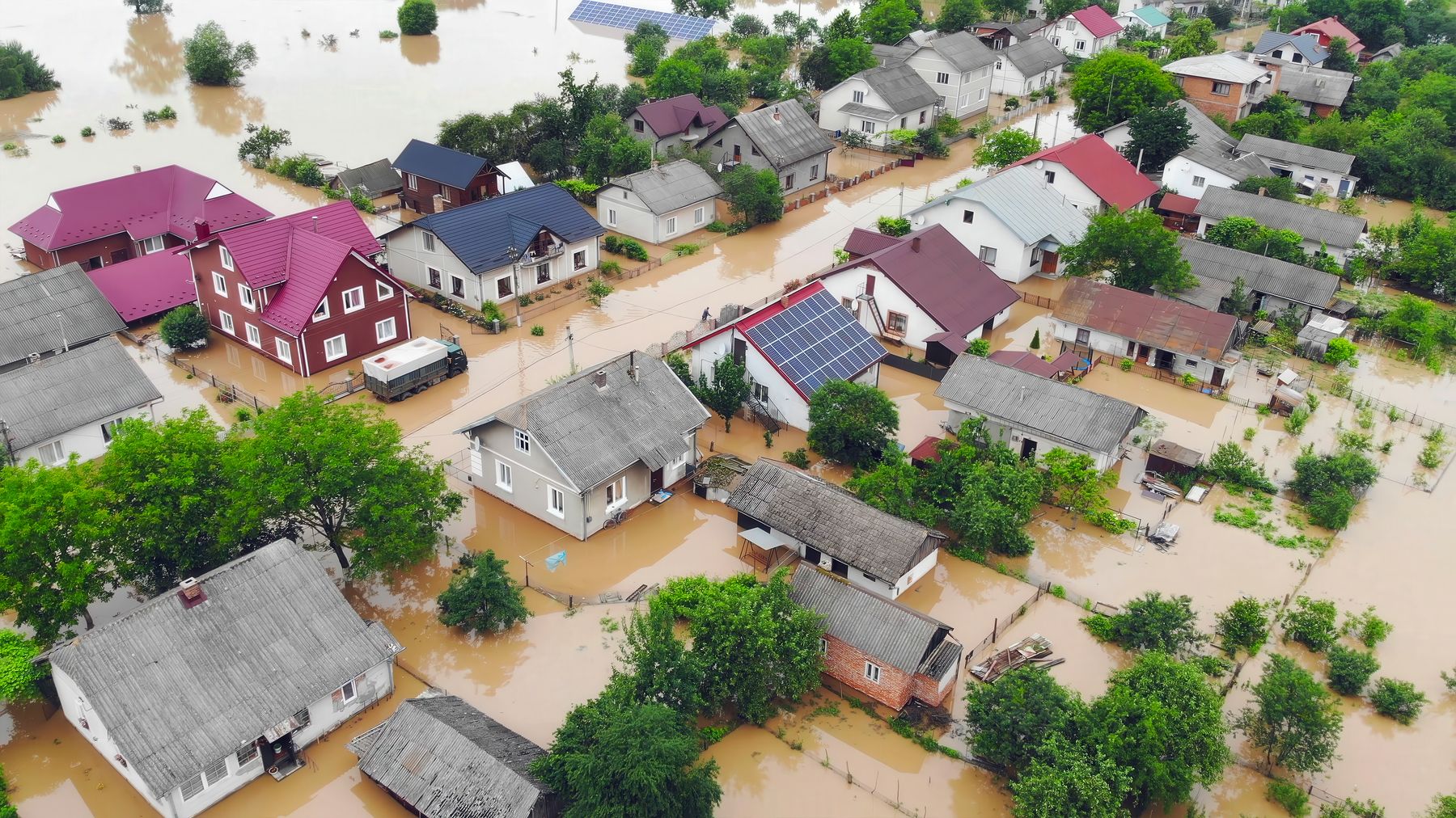 Vista aérea de un barrio residencial inundado, con agua cubriendo calles y patios